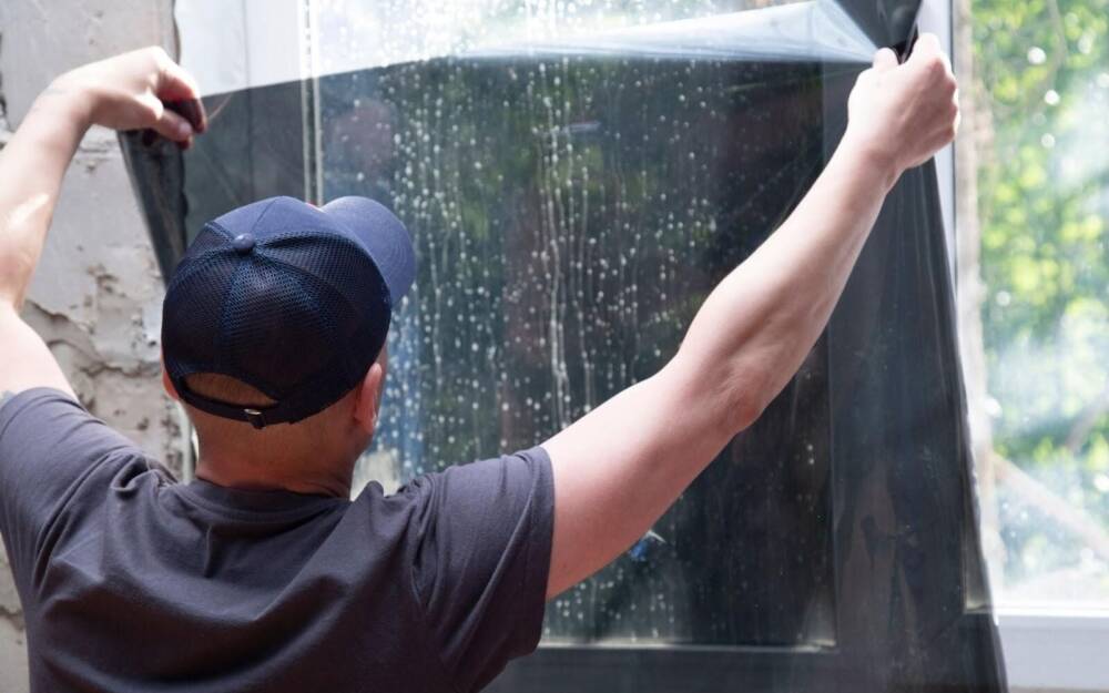 Man Applying Dark Tint Sheet To Window