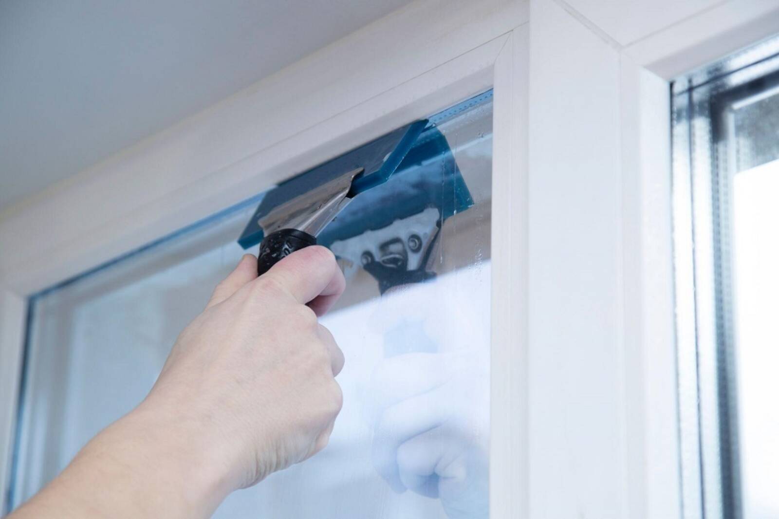 Man Fixing Bubble In The Window Film With Tool